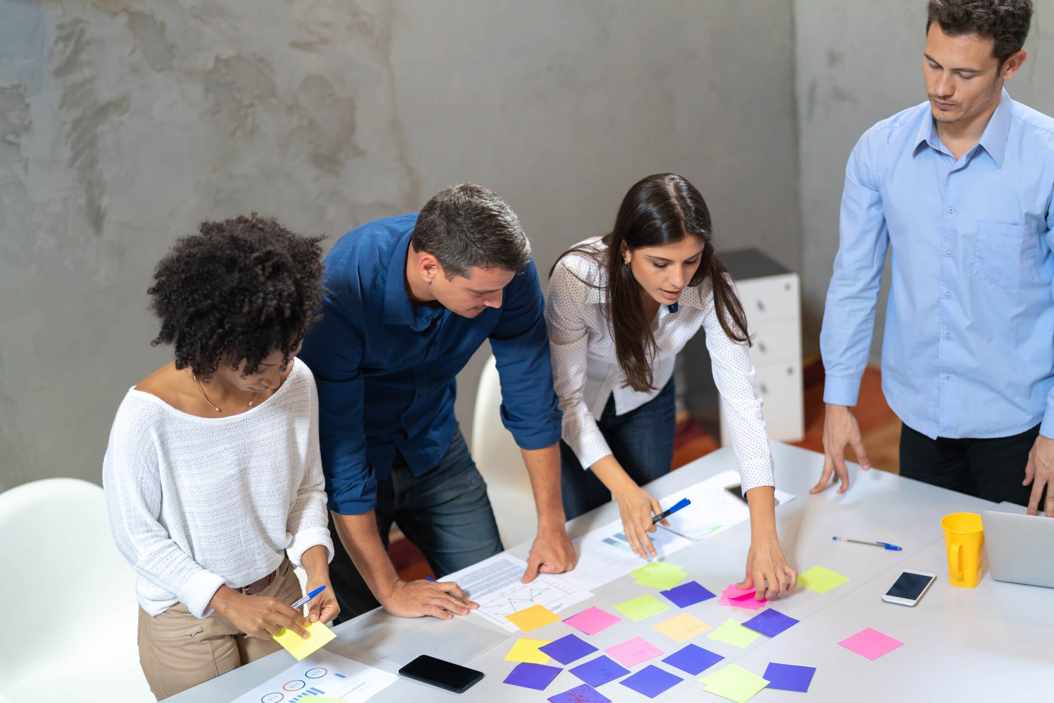 design thinking: equipe colando post its na mesa fazendo uma analise